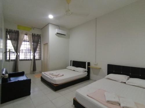 a bedroom with two beds and a chair in it at Promenade Homestay 2 in Kampong Sura Masjid