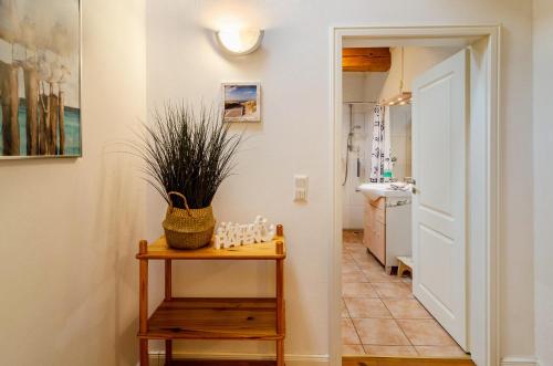 a hallway with a table and a bathroom with a sink at Gulfhof Oldersum Erdgeschoss in Moormerland