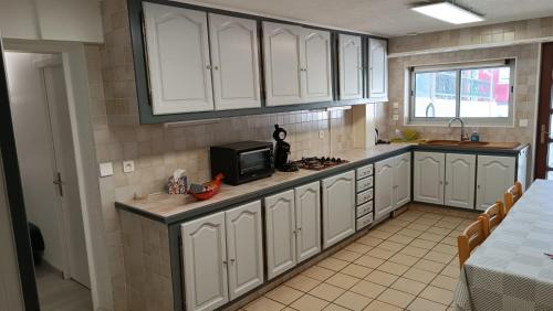 una cocina con armarios blancos y un microondas en Chez Léa, en Bourges