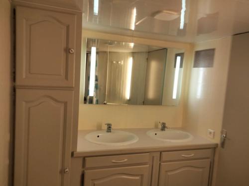 un baño con dos lavabos y un espejo en Chez Léa, en Bourges