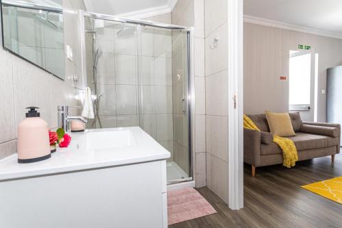 a bathroom with a sink and a shower and a couch at Oásis Fonte Grande in Ponta Delgada