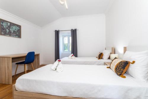 two beds in a room with a desk at Oásis Fonte Grande in Ponta Delgada