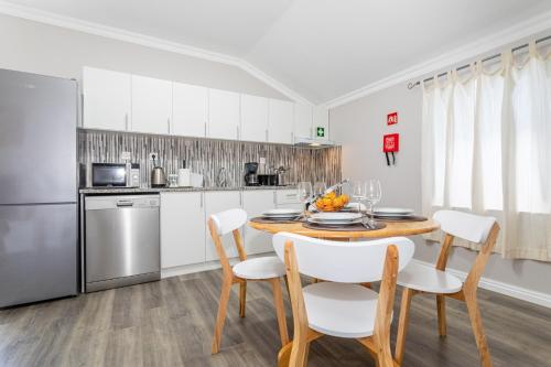 a kitchen with a table and chairs and a refrigerator at Oásis Fonte Grande in Ponta Delgada
