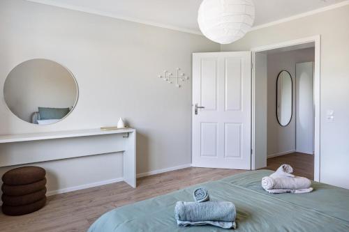 a white bedroom with a bed and a mirror at Zimis Hofnest in Freiamt