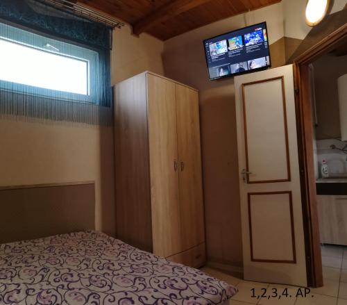 a bedroom with a bed and a cabinet and a television at CSABA-EMILKA-SPA Apartmanok in Hajdúszoboszló
