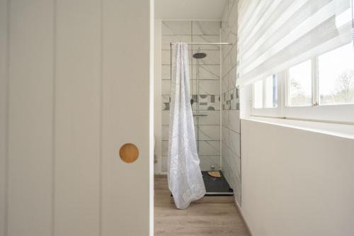 a white bathroom with a shower and a window at Au petit chez nous in Cozes