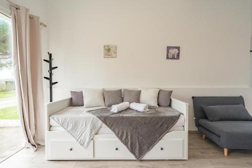 a white bed in a room with a couch at Au petit chez nous in Cozes