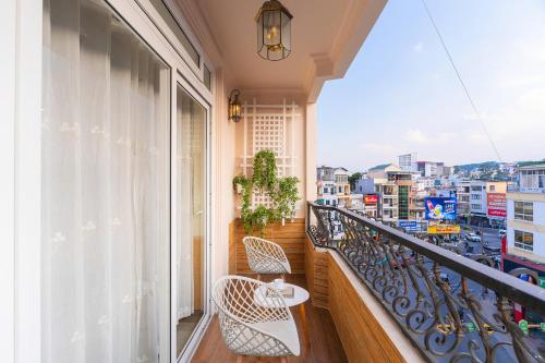 a balcony with two chairs and a view of a city at Sweet Lavender Hotel - Ngay chợ đêm Đà Lạt in Da Lat