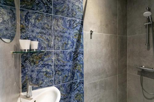 a bathroom with a sink and a shower with blue tiles at Villa Ker Louise in Locquirec