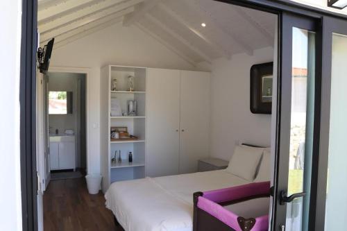 a bedroom with a white bed and a purple chair at Casa do Mestre Inteira in Vila de Punhe