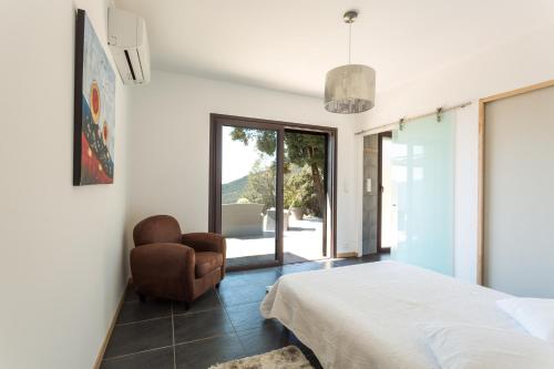 a bedroom with a bed and a chair at Villa Kalliste in Olmeto