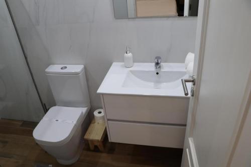 a white bathroom with a toilet and a sink at Casa do Mestre Inteira in Vila de Punhe