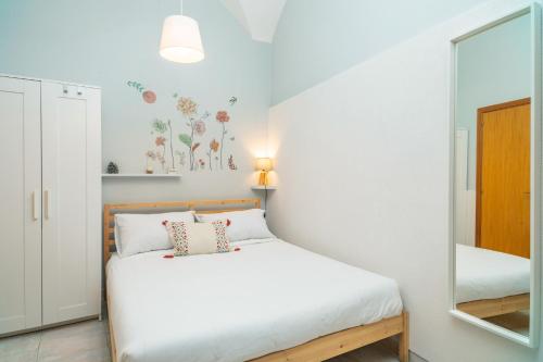 a bedroom with a white bed and a mirror at Casa Idda in Linguaglossa