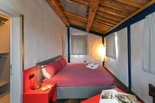 a small bedroom with a red bed and a table at Le Sughere in Riparbella