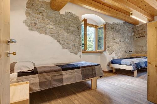 a bedroom with two beds and a stone wall at Casa al Mulino 1 in Tenno
