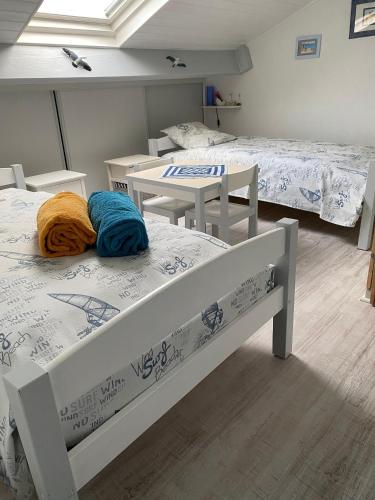 a room with two beds and a table and chairs at La Voile Blanche - 36 in Pornic