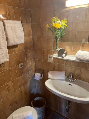 a bathroom with a sink and a toilet and a vase of flowers at Oberbründlingchalet in Taxenbach