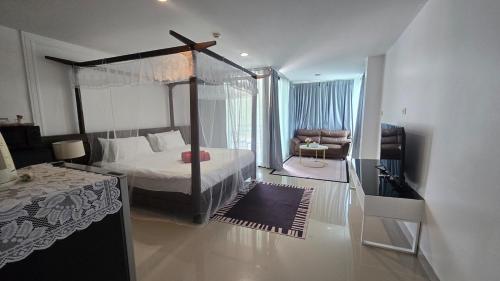 a bedroom with a canopy bed and a living room at joyful theKris 205 in Ban Lum Fuang