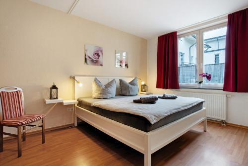 a bedroom with a bed with red curtains and a chair at Wohnung C1 - Haus A Cappella in Binz