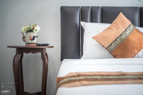 a bed with a pillow and a vase of flowers on a table at Retro Twin Home @Maesot in Mae Sot