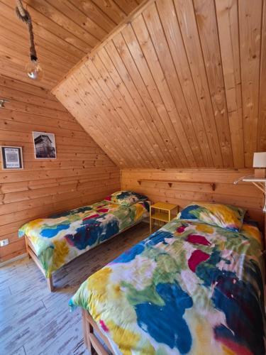 a bedroom with two beds in a wooden cabin at Domki przy Młynie " Koło Młyńskie " in Krościenko