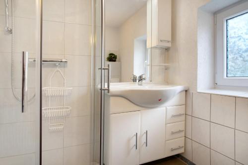 a white bathroom with a sink and a shower at De lütt Stuf - Urlaub mit Hund in Born