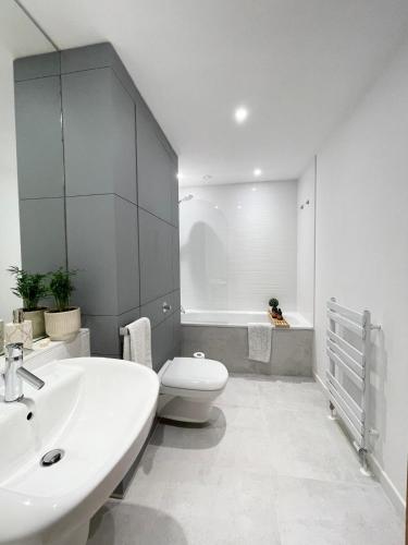 a white bathroom with a sink and a toilet at Private room and bathroom in shared flat with parking in Glasgow