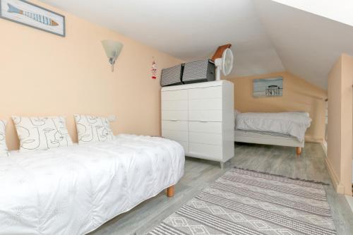 a bedroom with a white bed and a dresser at Appartement face mer et Piscine in Le Croisic