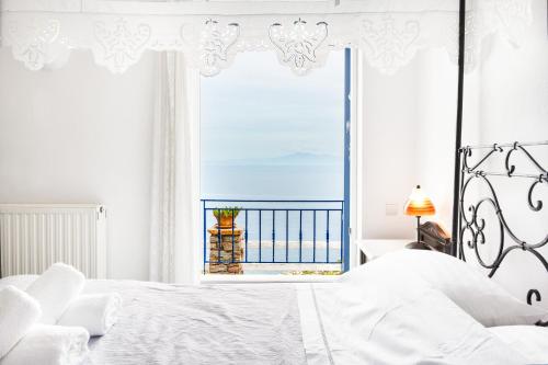 a white bedroom with a view of the ocean at Blue and White in Otziás