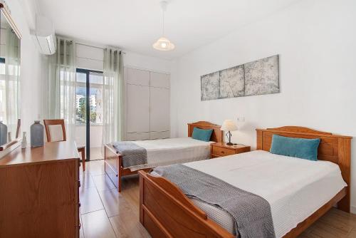 a bedroom with two beds and a desk and window at Abertura Mar Zen in Quarteira
