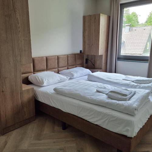 a bedroom with two beds with white sheets and a window at Wellnessappartement Winterberg D4 in Winterberg