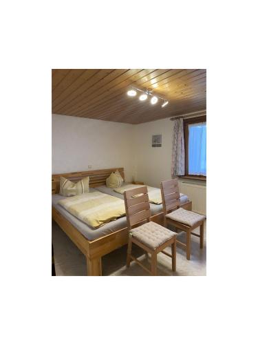 a bedroom with a large bed and two chairs at Ferienwohnung Wernet in Schönwald