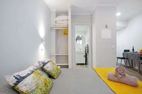 a bedroom with a bed with pillows and a kitchen at Família Dória Nóbrega T0 in Funchal