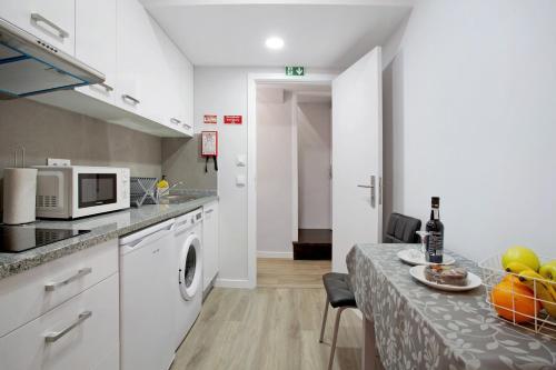 a kitchen with white cabinets and a table with a plate of food at Família Dória Nóbrega T0 in Funchal