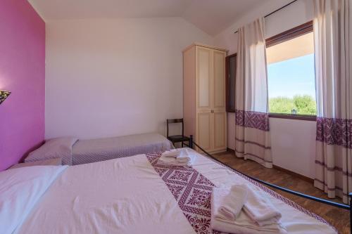 a small room with two beds and a window at Casa Ginestre piscina e vista mare in Aglientu