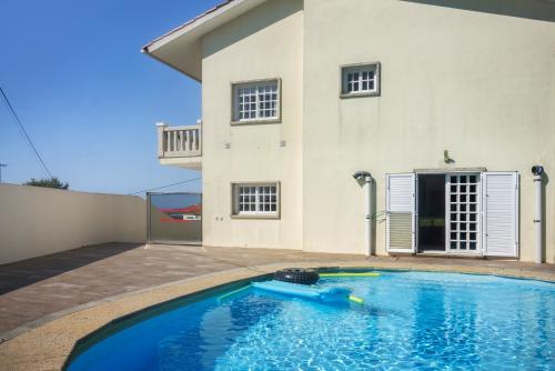 a swimming pool in front of a house at Casa Dona Lola in Moledo