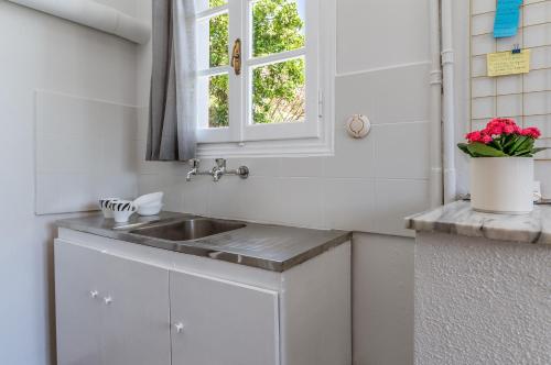 a white kitchen with a sink and a window at Stenies'nook in Andros