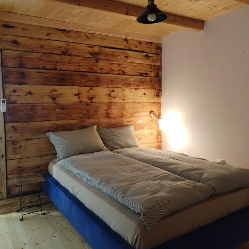 a bed in a room with a wooden wall at Zlatibor Koliba Laki in Zlatibor