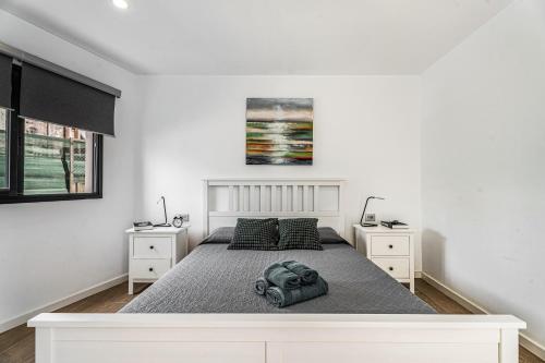 a white bedroom with a bed and two night stands at Casita El Pleito in Candelaria