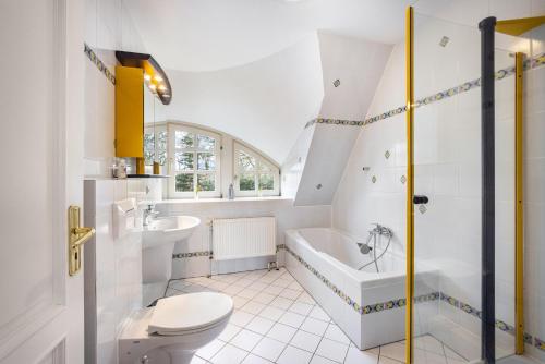 a white bathroom with a tub and a toilet and a sink at Ferienwohnung Gestüt Kriseby in Lübeck