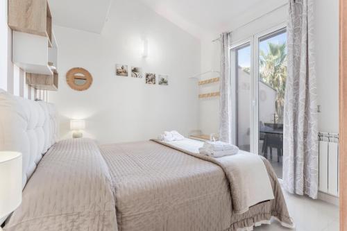 a white bedroom with a bed and a window at Olimar Home in Santa Flavia