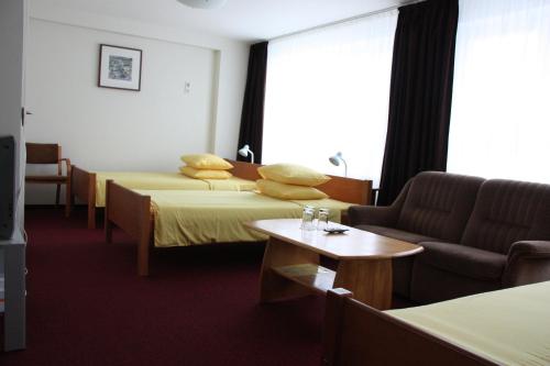 a hotel room with two beds and a couch at Hotel Madona in Madona