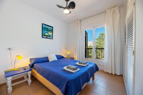 a bedroom with a bed with blue sheets and a window at Apartamento Isla Blanca in Es Pujols