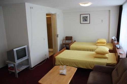 a hotel room with two beds and a tv at Hotel Madona in Madona