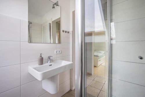 a white bathroom with a sink and a shower at Ferienwohnung Krempermoor 2 in Krempermoor