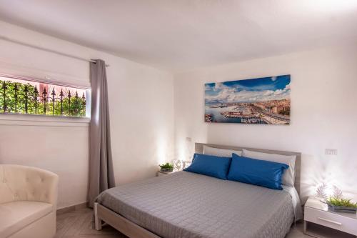 a white bedroom with a bed and a chair at Casa Petunia in Sarroch