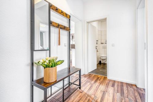 a hallway with a mirror and a table with flowers on it at Wohnung am Hagener Hbf - 4 Og in Hagen