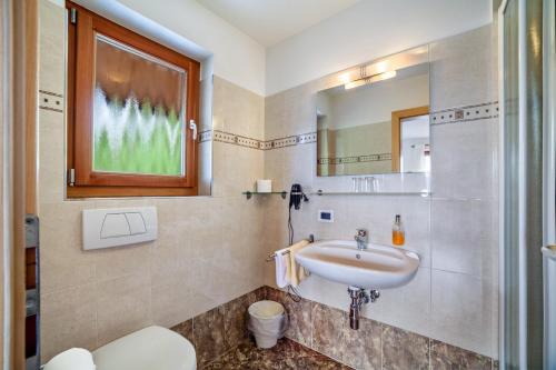 a bathroom with a sink and a toilet and a mirror at Hotel Klausthaler in Meltina