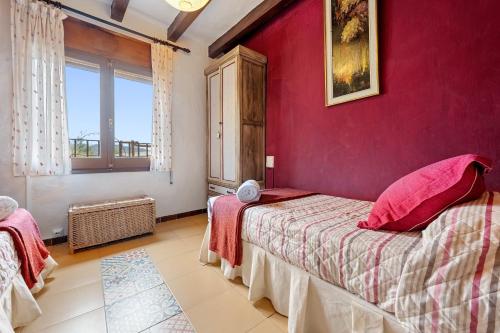 a bedroom with red walls and a bed with pink pillows at Priorat Tranquil in Lloá