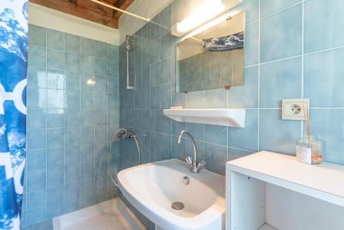 ein blau gefliestes Badezimmer mit Waschbecken und Spiegel in der Unterkunft Gite Lieuj in Peyrouse